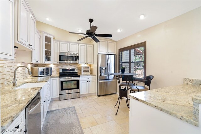 kitchen featuring stainless steel appliances, sink, decorative backsplash, ceiling fan, and white cabinets