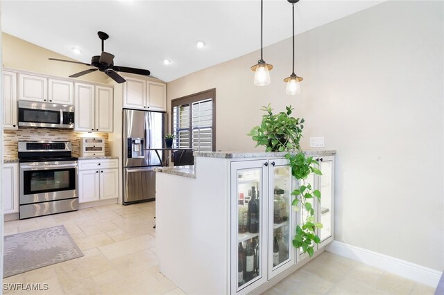 kitchen featuring light stone counters, stainless steel appliances, lofted ceiling, kitchen peninsula, and ceiling fan