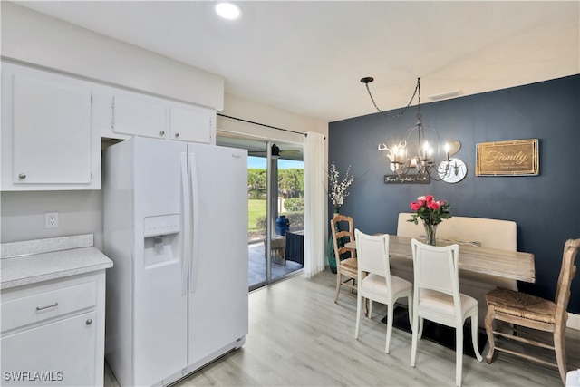 kitchen with white fridge with ice dispenser, light hardwood / wood-style flooring, a chandelier, hanging light fixtures, and white cabinets