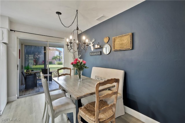 dining room with light wood finished floors, a notable chandelier, baseboards, and visible vents