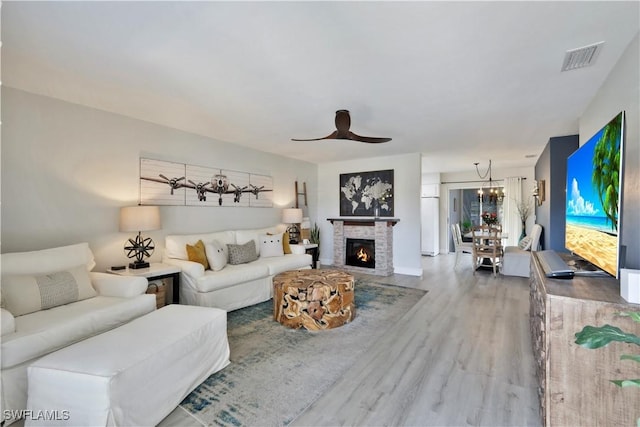 living area featuring ceiling fan, a fireplace, visible vents, and wood finished floors