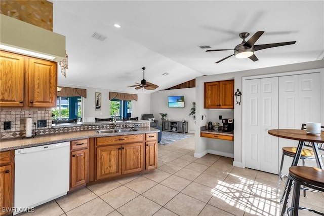 kitchen featuring white dishwasher, light tile patterned floors, sink, and vaulted ceiling