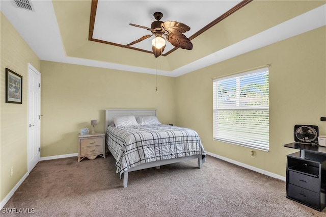 bedroom featuring ceiling fan, a raised ceiling, carpet floors, and crown molding