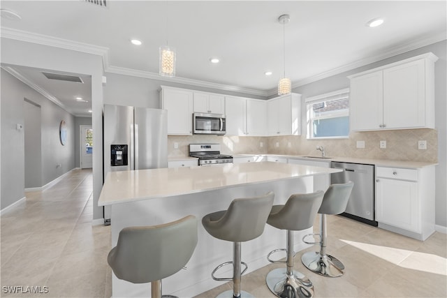 kitchen with pendant lighting, a kitchen island, white cabinets, and stainless steel appliances