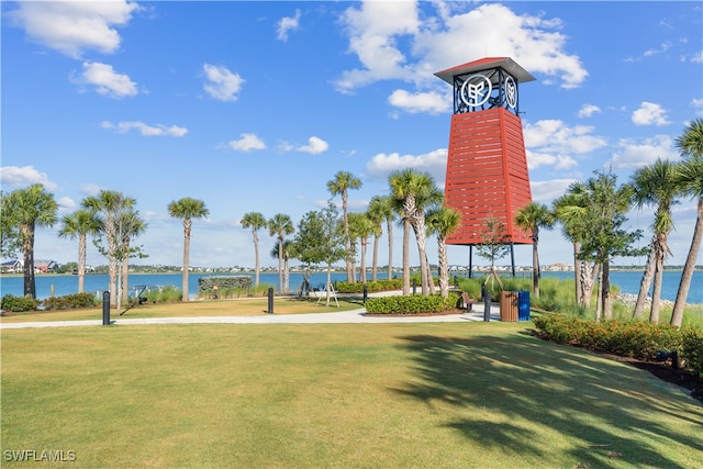 surrounding community with a water view and a lawn