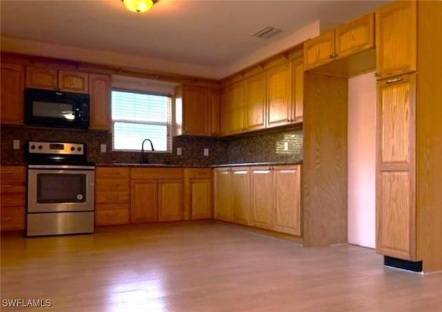 kitchen with backsplash, sink, dark stone countertops, light wood-type flooring, and range with electric stovetop