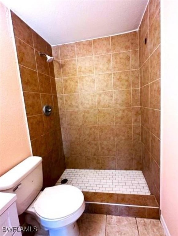 bathroom featuring tiled shower, toilet, tile patterned flooring, and vanity