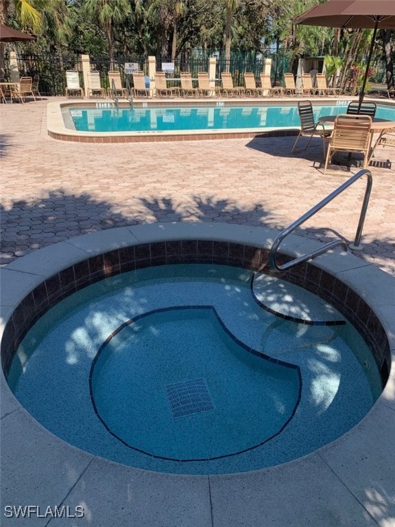 view of swimming pool featuring a hot tub and a patio area