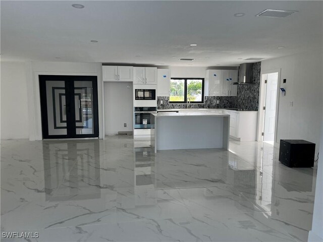 kitchen with light tile patterned floors, white cabinets, wall chimney exhaust hood, and black appliances