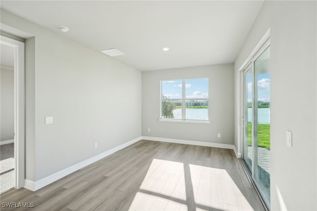 spare room with light wood-type flooring and a water view