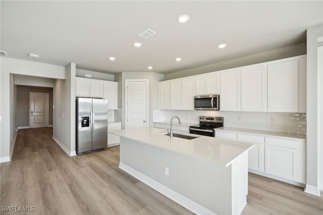 kitchen with light wood-type flooring, sink, white cabinetry, a center island with sink, and appliances with stainless steel finishes