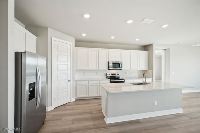 kitchen featuring an island with sink, appliances with stainless steel finishes, sink, and white cabinetry