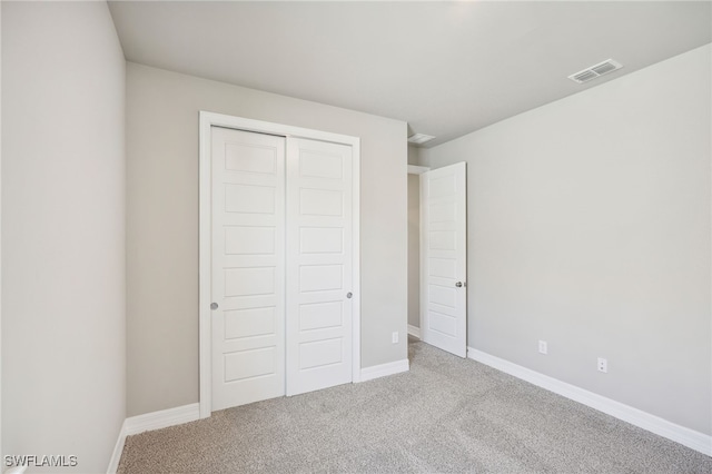 unfurnished bedroom featuring light carpet and a closet