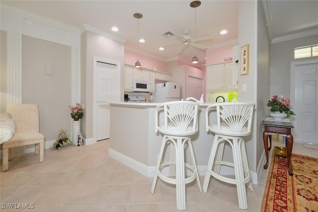 kitchen featuring a kitchen bar, white appliances, ceiling fan, white cabinetry, and kitchen peninsula