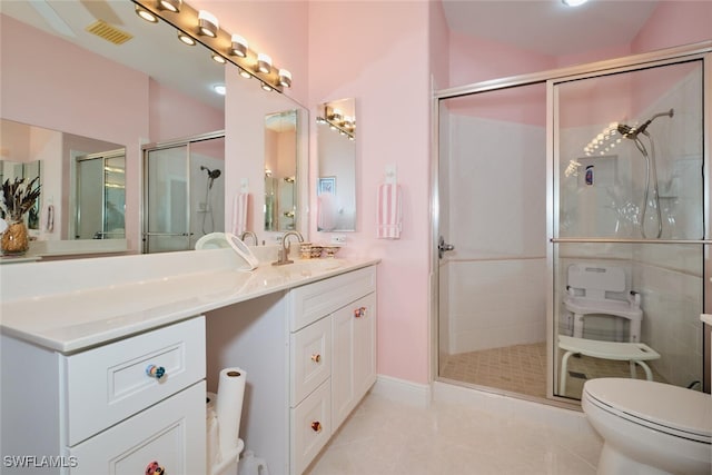 bathroom featuring toilet, vanity, walk in shower, and tile patterned floors