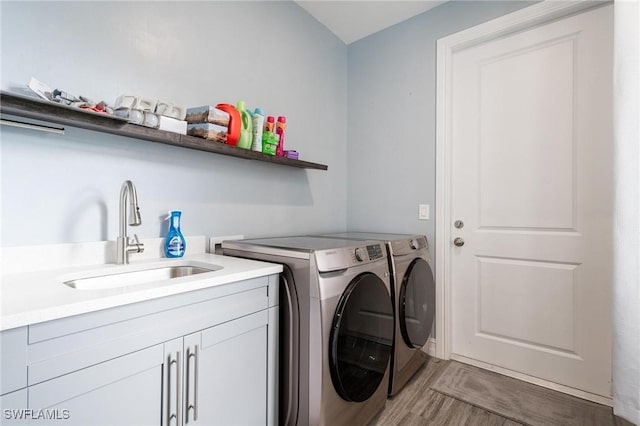 laundry area featuring cabinets, light wood-type flooring, washer and clothes dryer, and sink