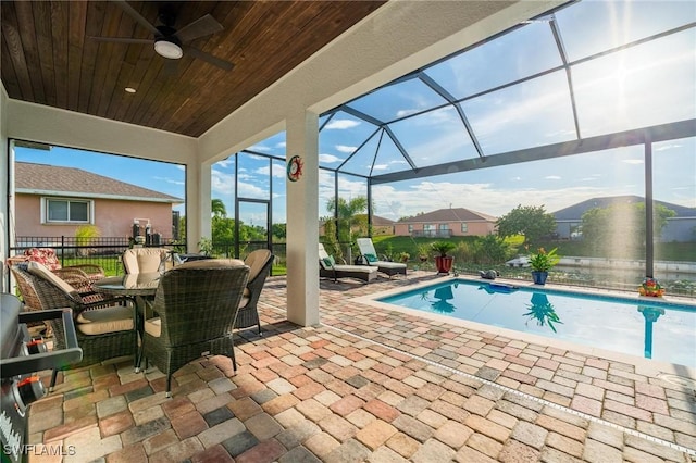 view of swimming pool with glass enclosure, ceiling fan, and a patio