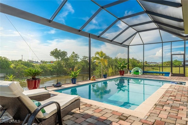 view of swimming pool with glass enclosure, a water view, and a patio