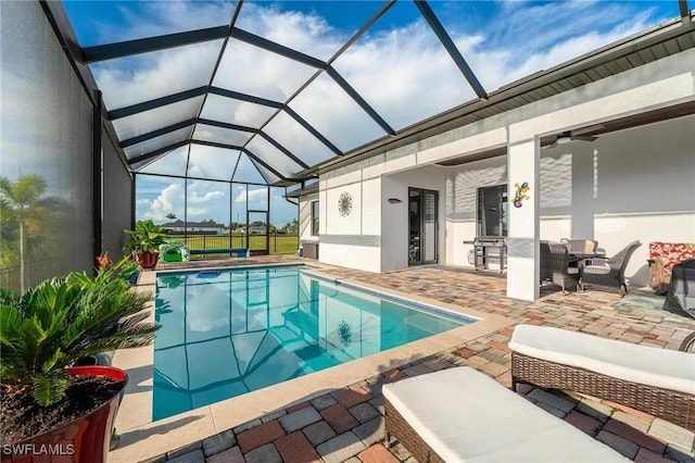 view of pool with a lanai, a patio area, and ceiling fan