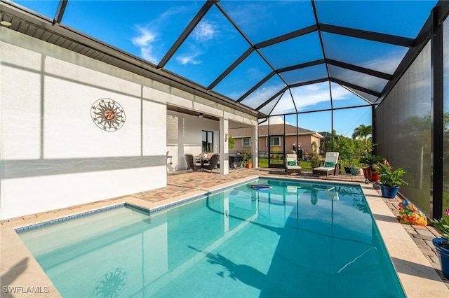 view of swimming pool with a patio area, ceiling fan, and glass enclosure