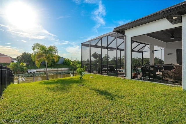 view of yard with a lanai, ceiling fan, a water view, and a patio