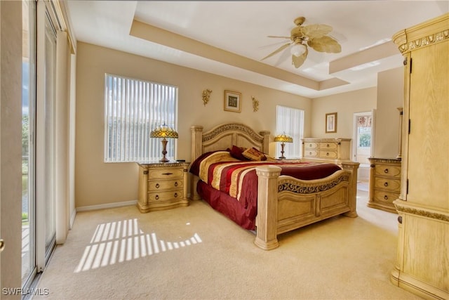 carpeted bedroom with ceiling fan, access to outside, and a tray ceiling