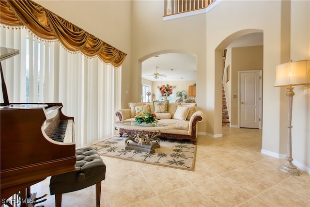 living area with light tile patterned floors, a towering ceiling, and ceiling fan