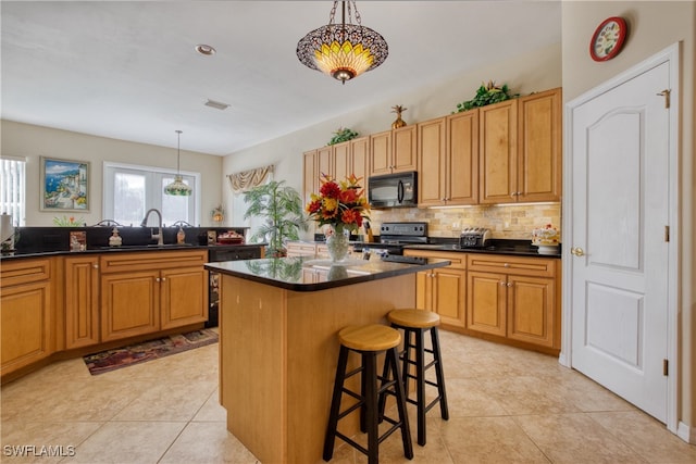 kitchen with backsplash, black appliances, a kitchen island, hanging light fixtures, and a breakfast bar area