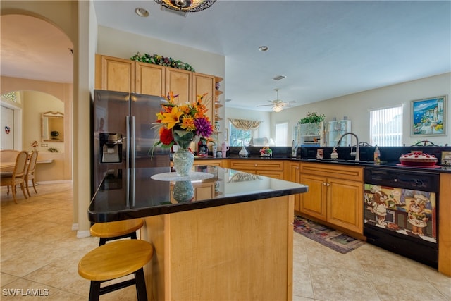 kitchen with ceiling fan, dishwasher, sink, kitchen peninsula, and a kitchen bar