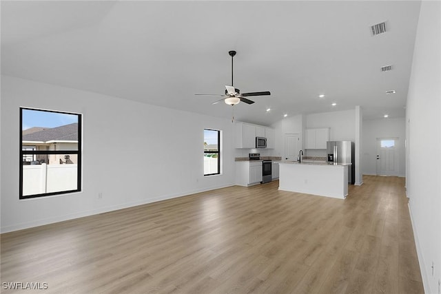 1310 Bush St W, Immokalee, FL 34142 - unfurnished living room featuring light wood-style floors, ceiling fan, vaulted ceiling, recessed lighting, and baseboards