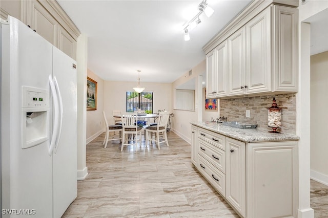 kitchen featuring track lighting, white fridge with ice dispenser, light stone countertops, pendant lighting, and tasteful backsplash