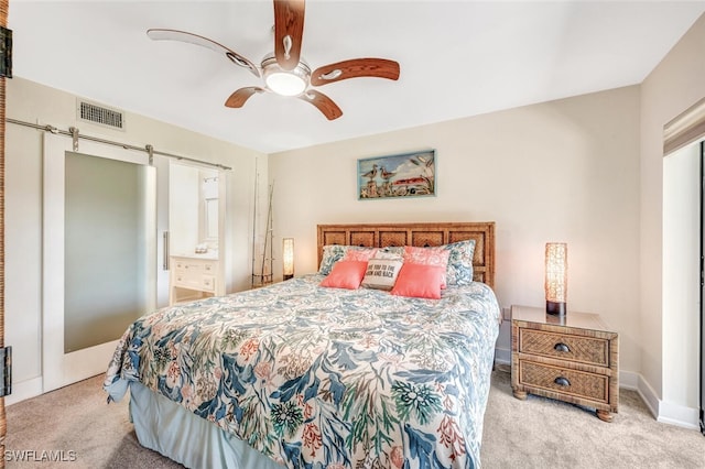 bedroom with light carpet, a barn door, connected bathroom, and ceiling fan