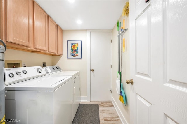 laundry area with light hardwood / wood-style flooring, washing machine and clothes dryer, and cabinets