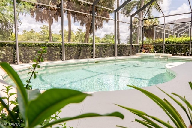 view of swimming pool with glass enclosure and a pool with connected hot tub