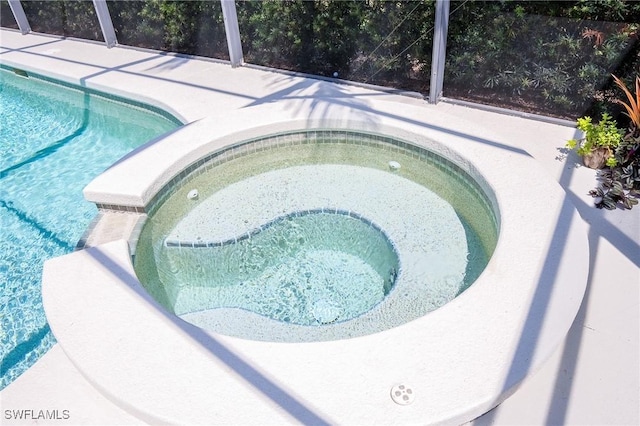 outdoor pool with a lanai, a patio area, and an in ground hot tub