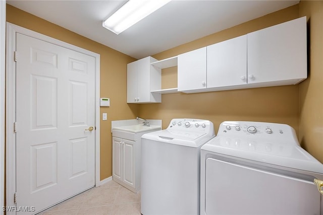 washroom featuring washer and dryer, cabinet space, a sink, and light tile patterned floors