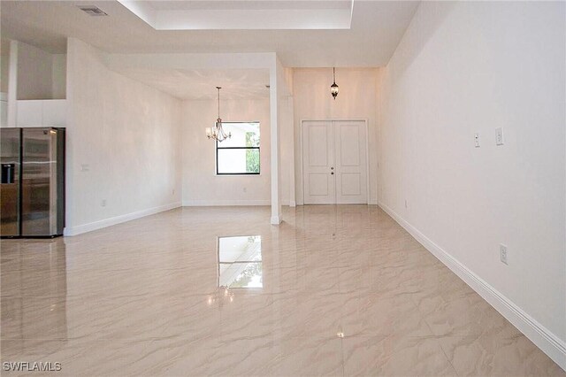 spare room featuring tile patterned flooring and a chandelier