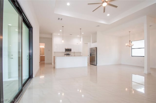 unfurnished living room featuring a tray ceiling, ceiling fan with notable chandelier, and light tile patterned floors