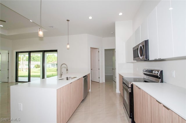 kitchen with stainless steel appliances, sink, an island with sink, pendant lighting, and light tile patterned flooring