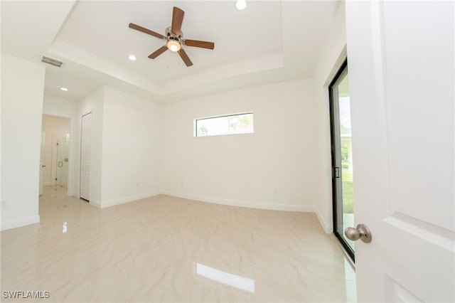 tiled spare room featuring ceiling fan and a tray ceiling