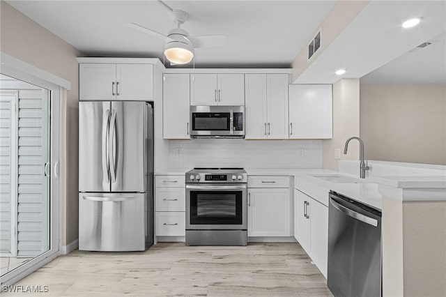 kitchen featuring tasteful backsplash, visible vents, appliances with stainless steel finishes, light countertops, and a sink