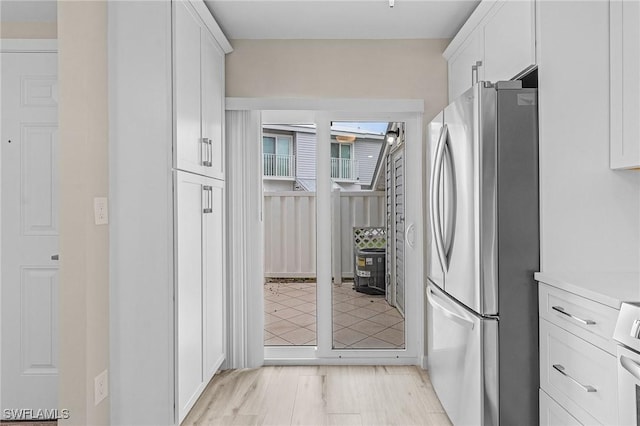 kitchen featuring light wood-type flooring, freestanding refrigerator, light countertops, and white cabinets