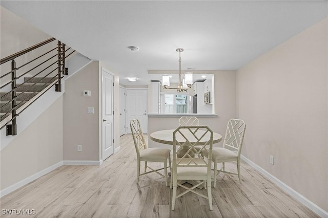 unfurnished dining area featuring baseboards, a chandelier, stairs, and light wood-style floors