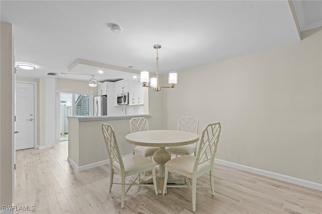 dining space with a chandelier, light wood-type flooring, and baseboards