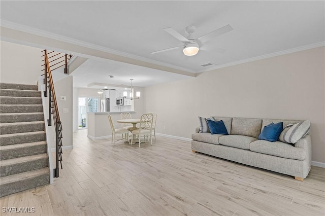 living room featuring visible vents, light wood-style flooring, ornamental molding, stairs, and ceiling fan with notable chandelier