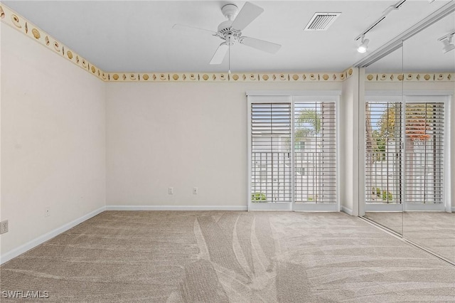 carpeted empty room with rail lighting, baseboards, visible vents, and a ceiling fan