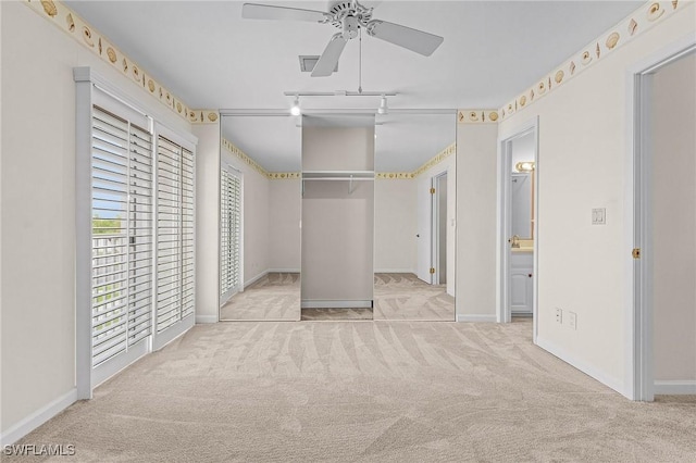 unfurnished bedroom with carpet, ensuite bathroom, a ceiling fan, track lighting, and baseboards