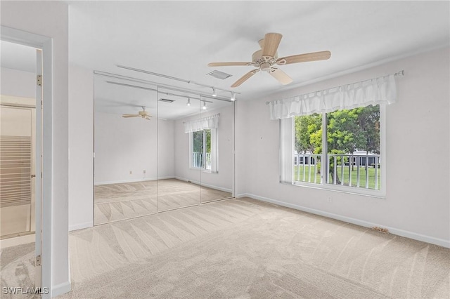 unfurnished room with visible vents, baseboards, a ceiling fan, rail lighting, and carpet