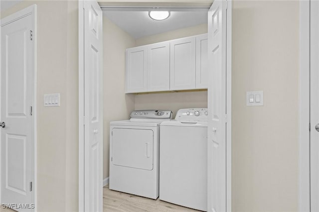 clothes washing area featuring cabinet space, light wood-style flooring, and independent washer and dryer