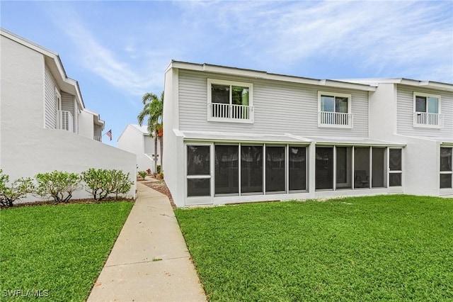 back of property with a sunroom and a lawn